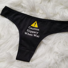 Load image into Gallery viewer, Caution Slippery When Wet text with caution sign above on a black thong