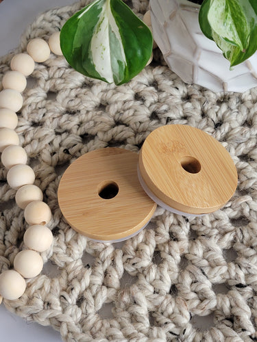 Two bamboo lids with straw holes for glass cans.