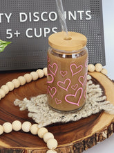 Load image into Gallery viewer, 16oz glass beer can shown with hearts design covering entire surface. Also shown with bamboo lid and glass straw.