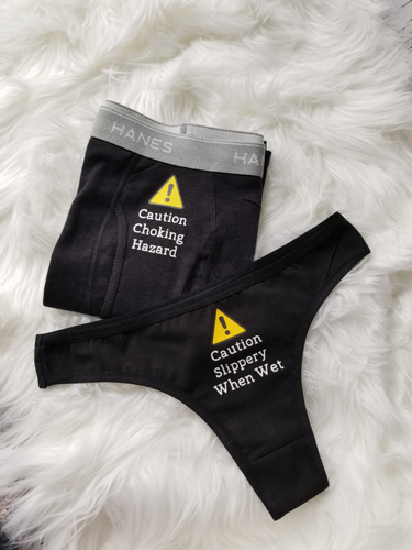 Funny Couple's Underwear Anniversary Gift. Men's black boxer with caution choking hazard design on crotch. black thong with caution slippery when wet design