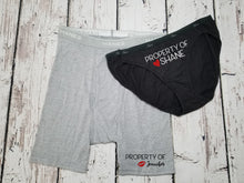 Load image into Gallery viewer, Men's Grey boxer briefs and black bikini style underwear. The design on the men's boxer briefs says Property of Jennifer with red kiss lips next to the name. The women's bikini says property of Shane with a red heart next to the name.