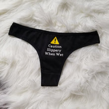 Load image into Gallery viewer, Caution Slippery When Wet text with caution sign above on a black thong
