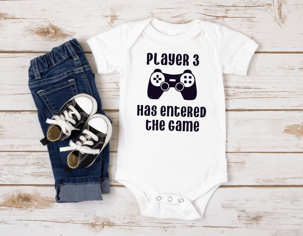 White baby bodysuit with picture of gaming controller. Text says 