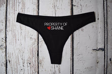 Load image into Gallery viewer, Women&#39;s black thong with the text property of Shane with a red heart next to the name. Text is white.
